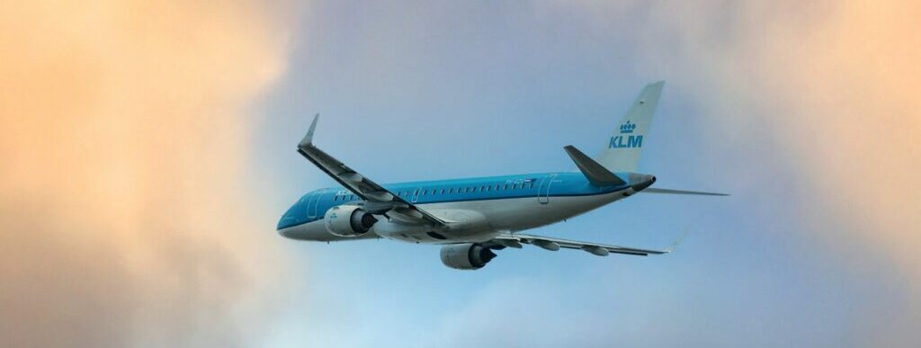 a blue and white airplane flying through a cloudy sky